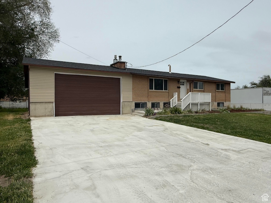 View of front of property featuring driveway, an attached garage, a chimney, and a front yard