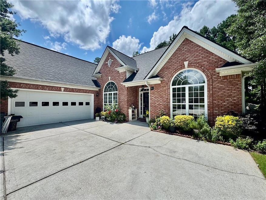 Traditional-style home featuring brick siding, driveway, an attached garage, and a shingled roof
