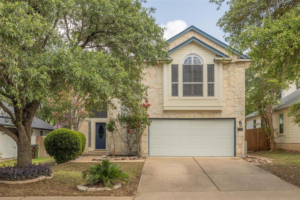 View of front of property featuring concrete driveway, an attached garage, and stone siding