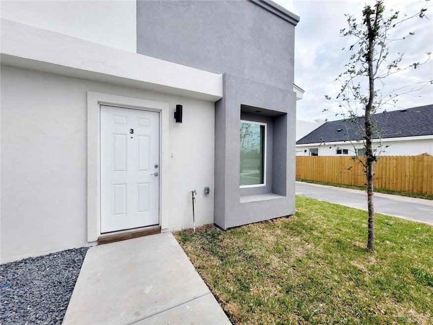 Entrance to property with fence, a lawn, and stucco siding