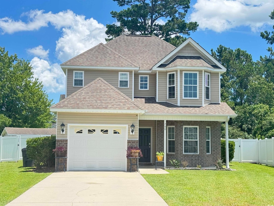 View of front of property featuring a gate, driveway, roof with shingles, and brick siding