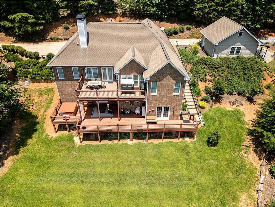 Rear view of house with a chimney, a deck, a yard, brick siding, and a wooded view