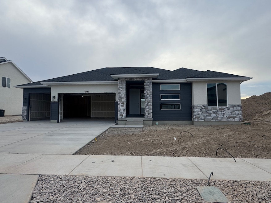 Prairie-style home with stone siding, concrete driveway, an attached garage, and stucco siding