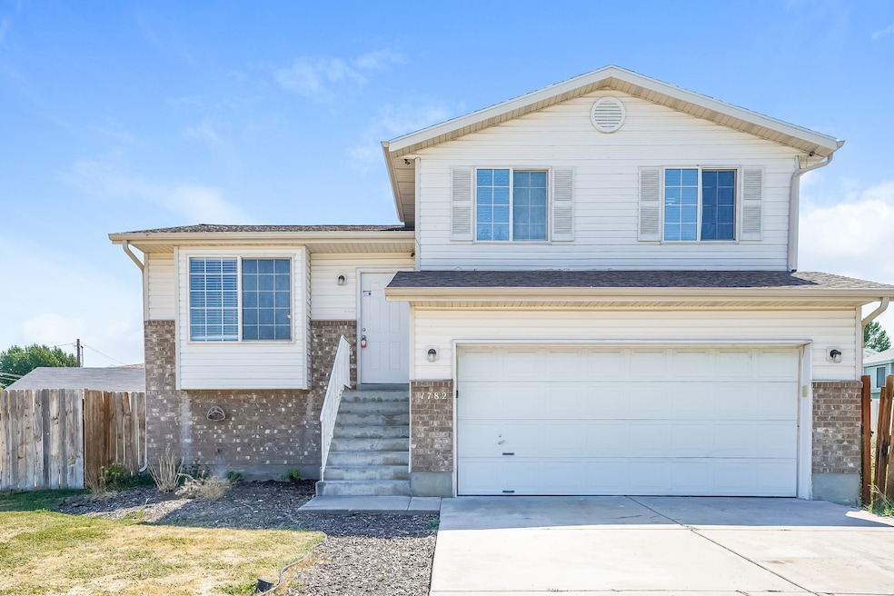 Split level home featuring an attached garage, driveway, a shingled roof, and brick siding