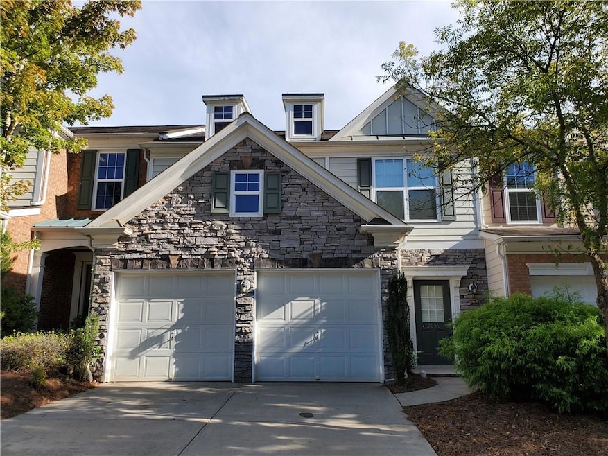 View of front facade with concrete driveway, stone siding, and an attached garage