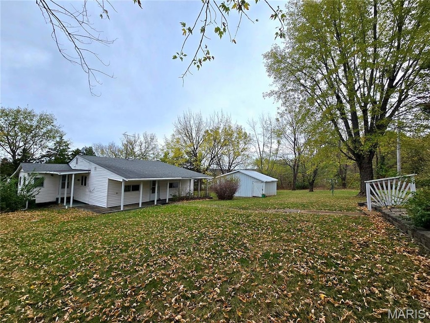 View of green lawn featuring an outbuilding and covered porch
