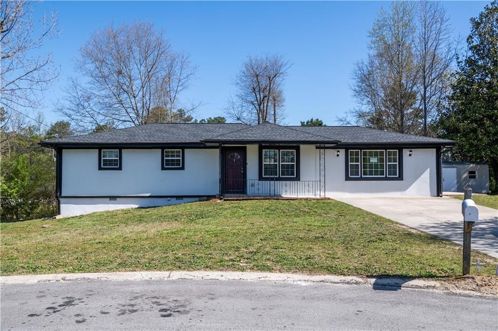 Ranch-style home featuring stucco siding, covered porch, concrete driveway, and a front yard