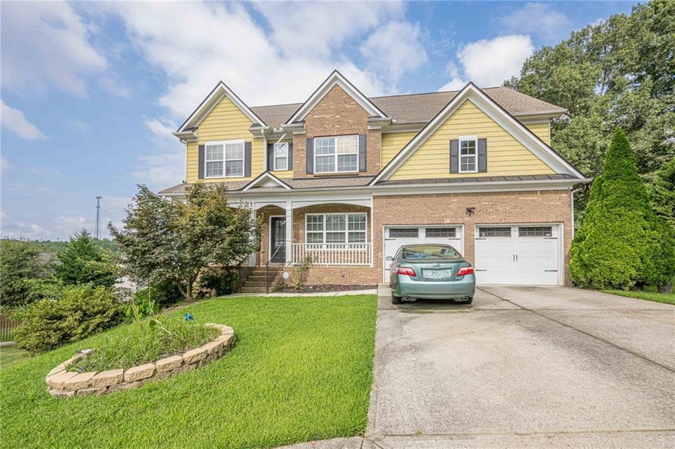 Traditional-style home with brick siding, concrete driveway, covered porch, and an attached garage
