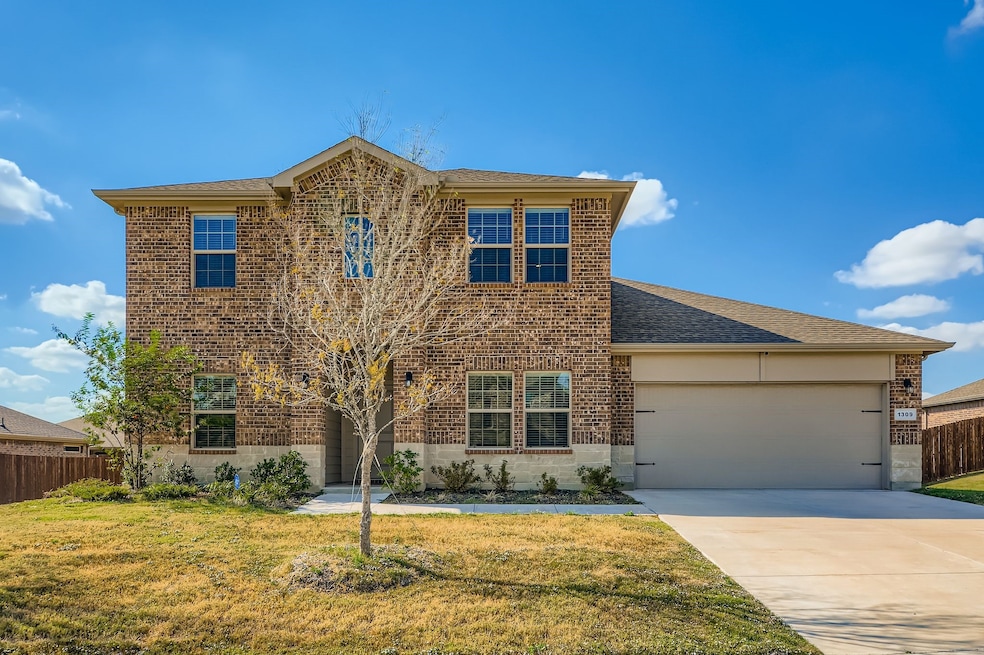 Traditional-style house with brick siding, driveway, an attached garage, and roof with shingles