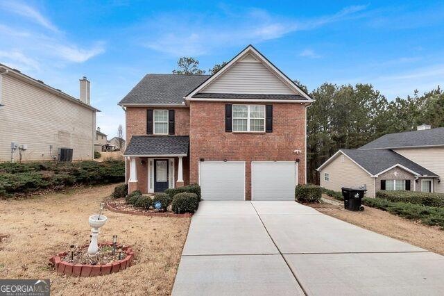 Traditional-style home with a garage, concrete driveway, and brick siding
