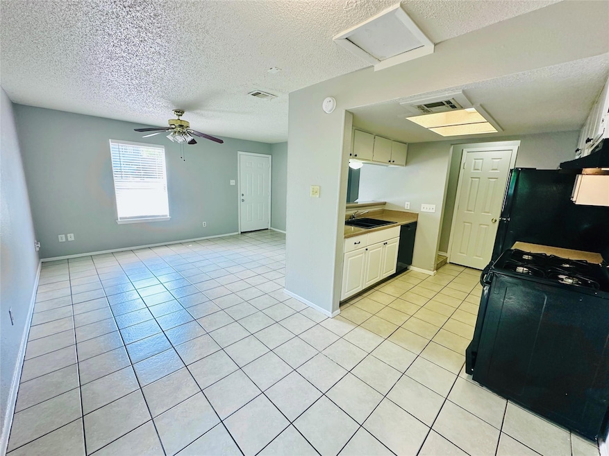 Kitchen with black appliances, a textured ceiling