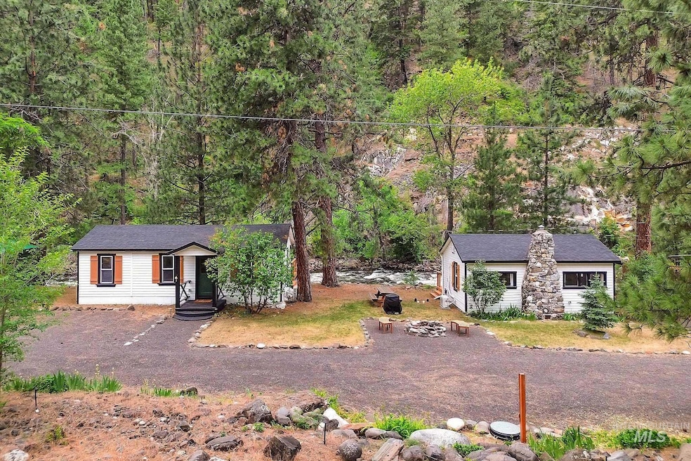View of front of property with a wooded view, an outdoor fire pit, and an outbuilding