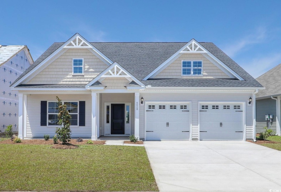 View of front of house featuring a shingled roof, an attached garage, driveway, and a front lawn