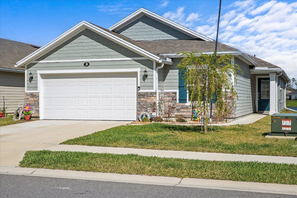 Craftsman-style house featuring stone siding, a front lawn, concrete driveway, and an attached garage