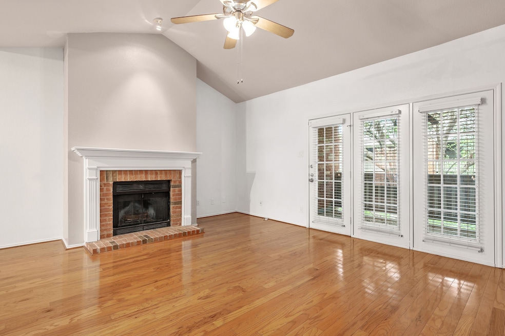 Unfurnished living room featuring ceiling fan, a fireplace, lofted ceiling, and hardwood / wood-style flooring