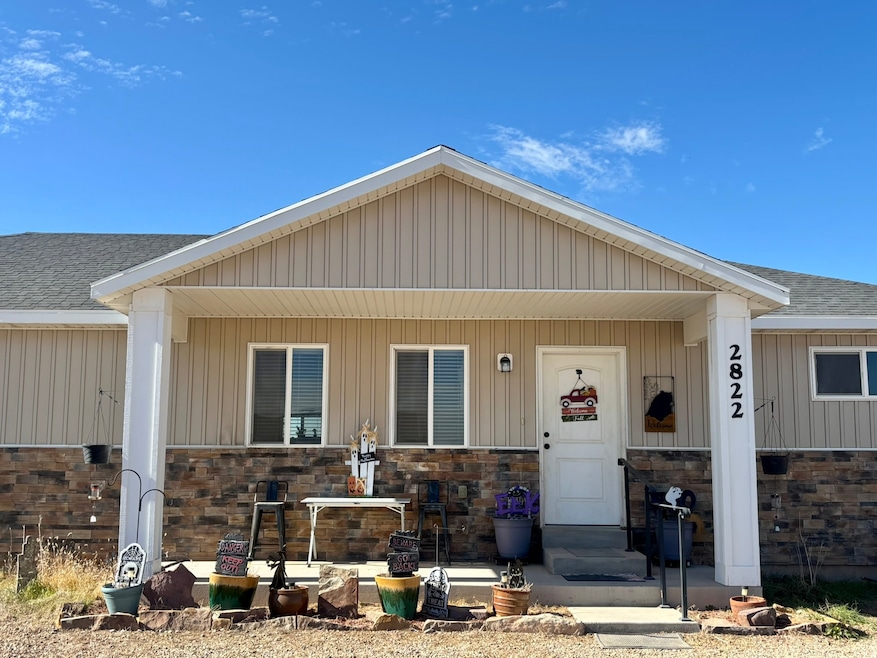 View of front of home featuring covered porch, board and batten siding, stone siding, and a shingled roof