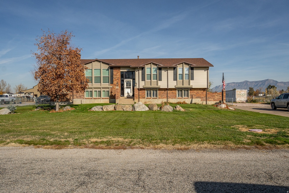 Raised ranch with brick siding, a front lawn, and a mountain view
