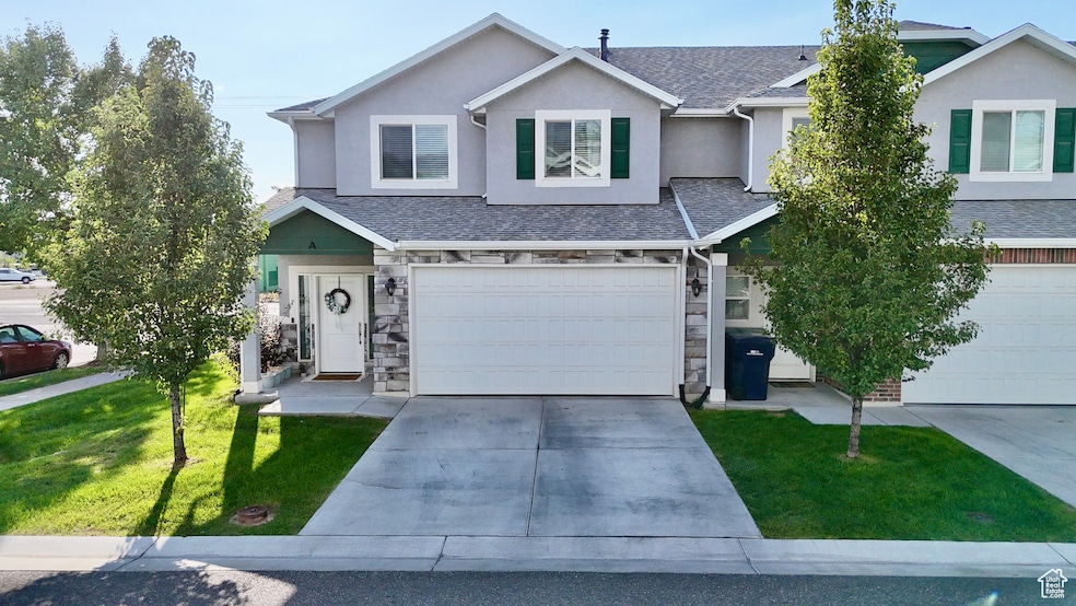 Traditional-style home featuring a front yard, driveway, stone siding, and a garage
