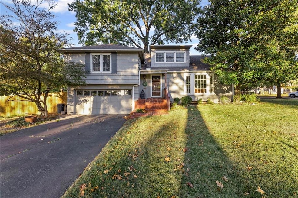 Split level home with asphalt driveway, a garage, and brick siding
