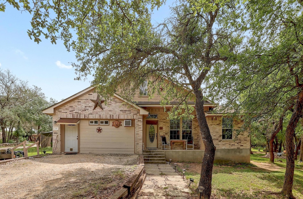 View of front facade with dirt driveway, an attac