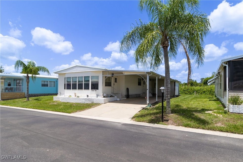 Manufactured / mobile home with a front lawn, driveway, and a carport