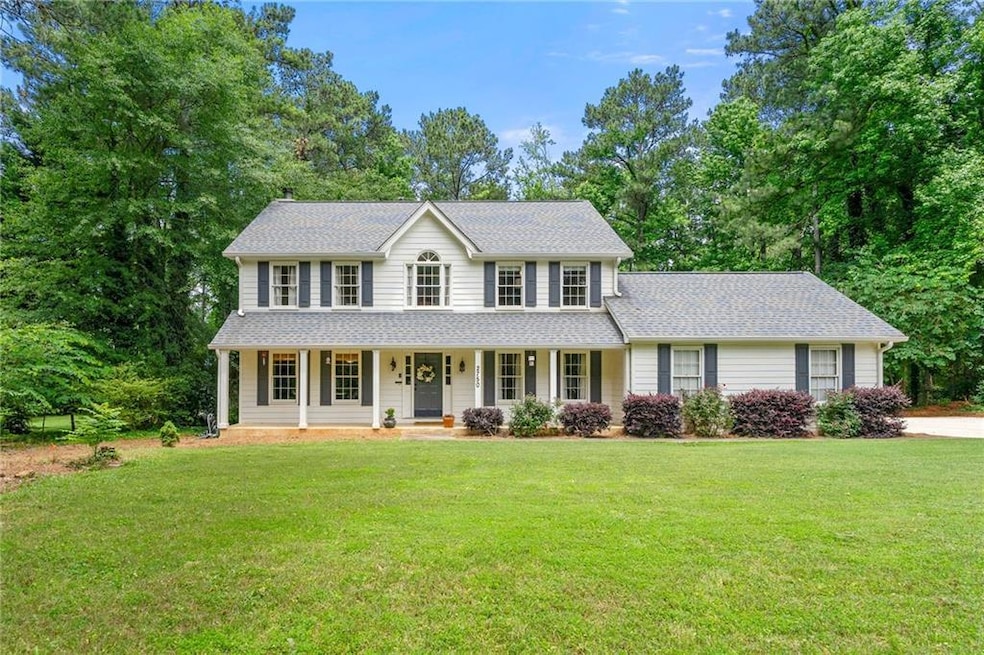 Colonial inspired home featuring covered porch, a front yard, and roof with shingles