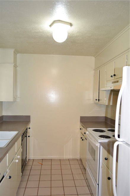 Kitchen featuring refrigerator, exhaust hood, white cabinetry, range, and dishwasher