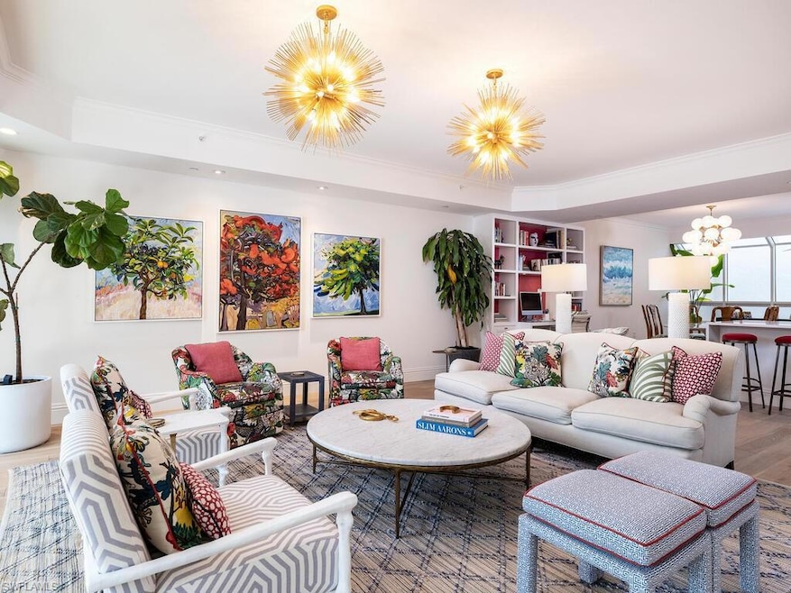 Living area with a chandelier, ornamental molding, wood finished floors, and a tray ceiling