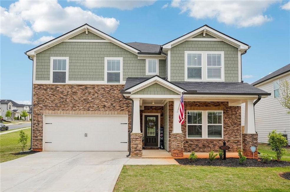 Craftsman-style home featuring driveway, stone sid