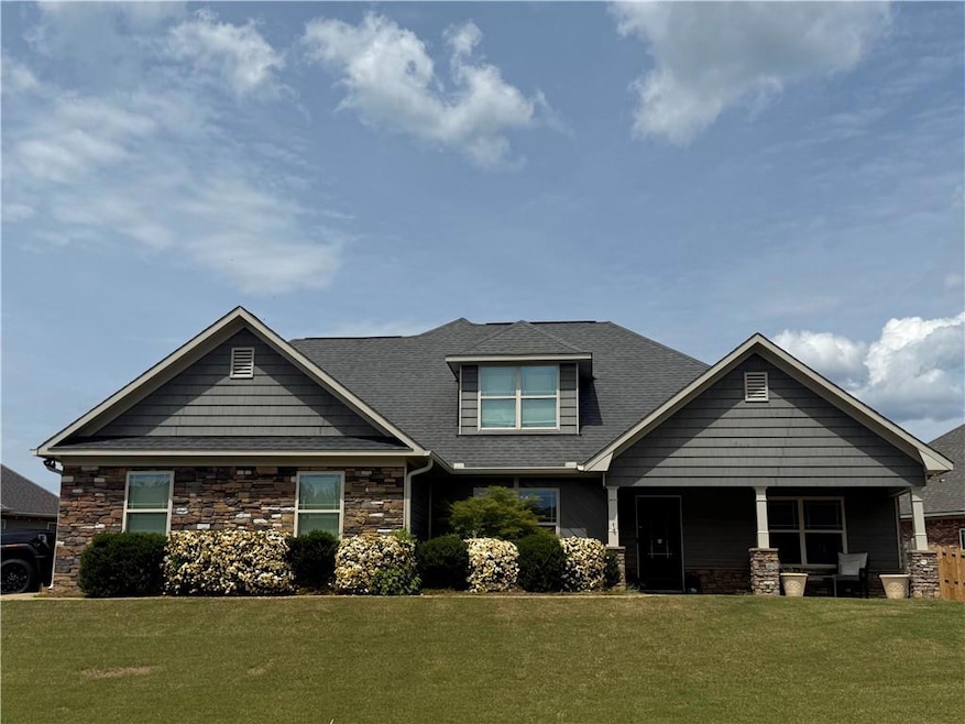 Craftsman house featuring stone siding, a front ya
