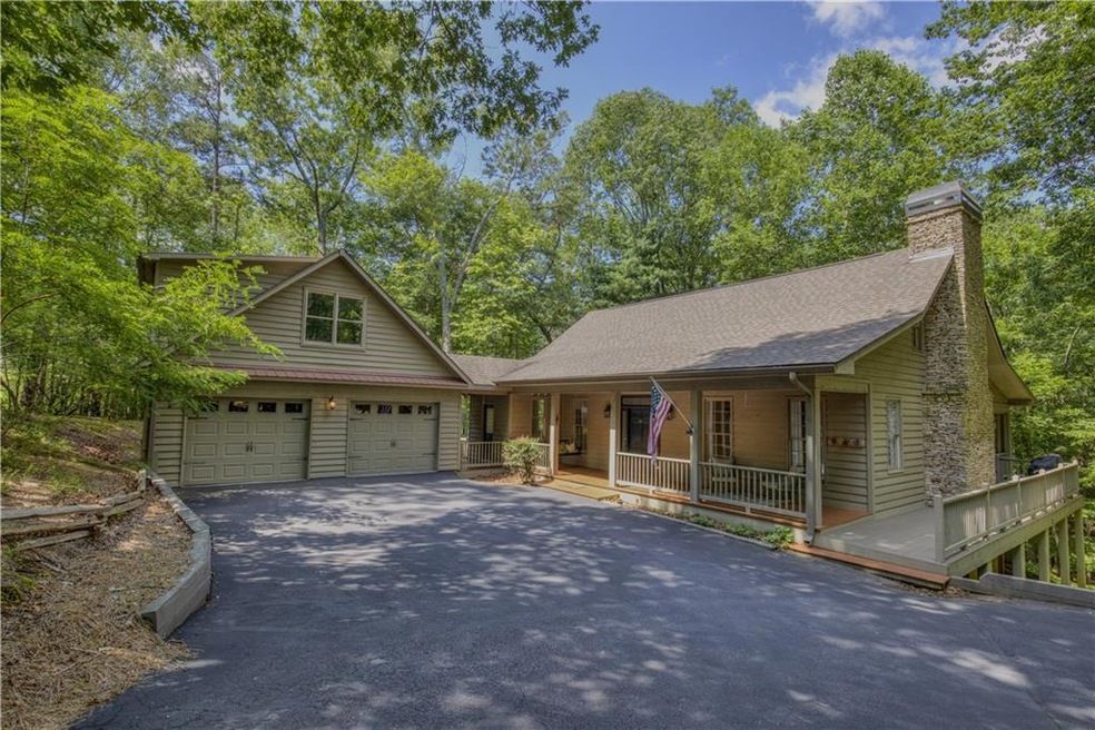 View of front of property with driveway, covered porch, a shingled roof, and a chimney