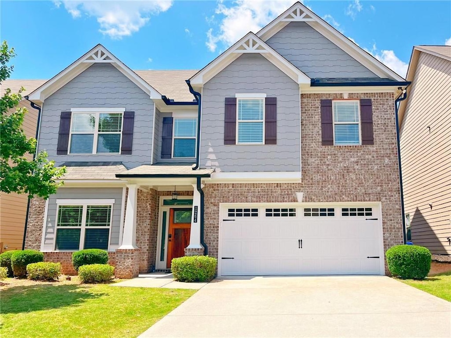 Craftsman inspired home with brick siding, an attached garage, concrete driveway, and a front lawn