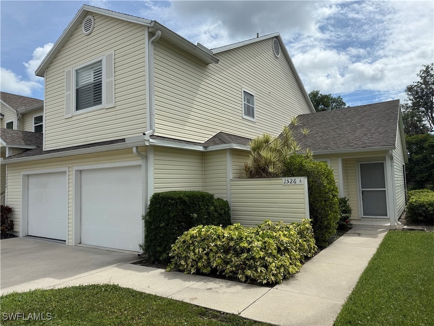 Traditional-style home with an attached garage, roof with shingles, and concrete driveway