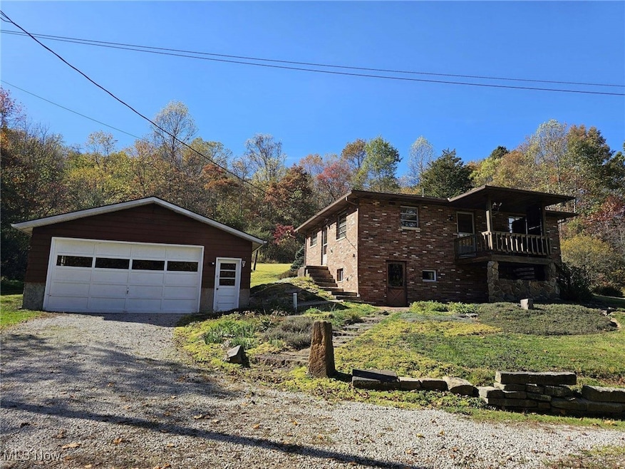 View of home's exterior with a detached garage, an outdoor structure, brick siding, and a balcony