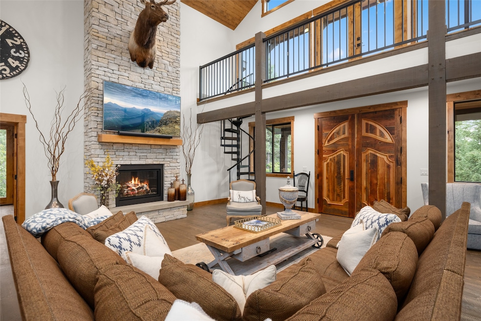 Living area featuring wood finished floors, high vaulted ceiling, a fireplace, stairway, and wood ceiling