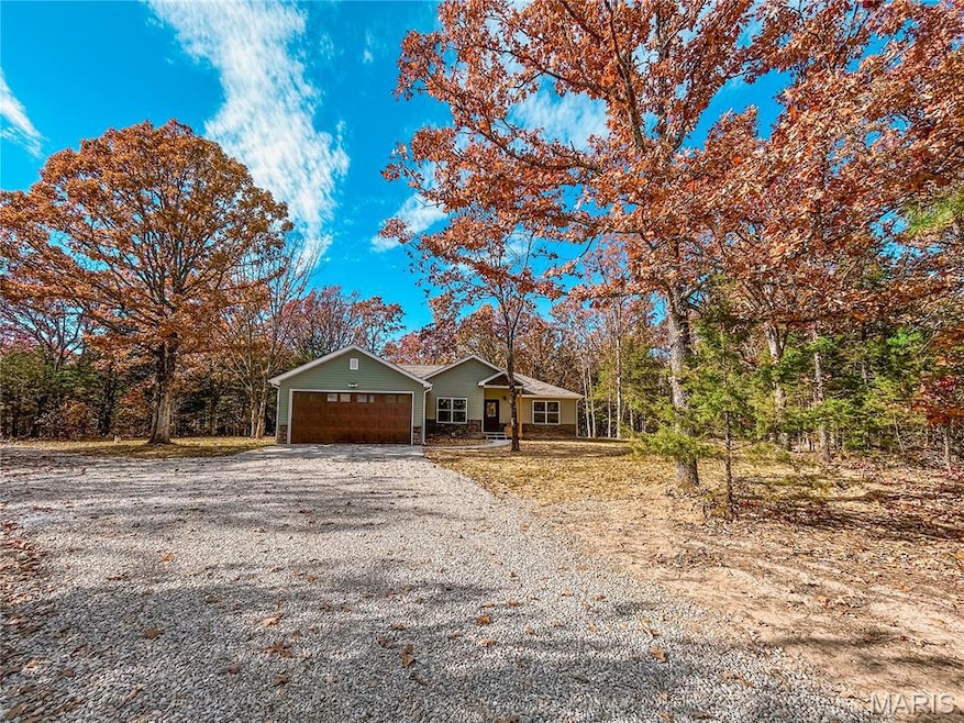 Ranch-style house featuring gravel driveway and an attached garage