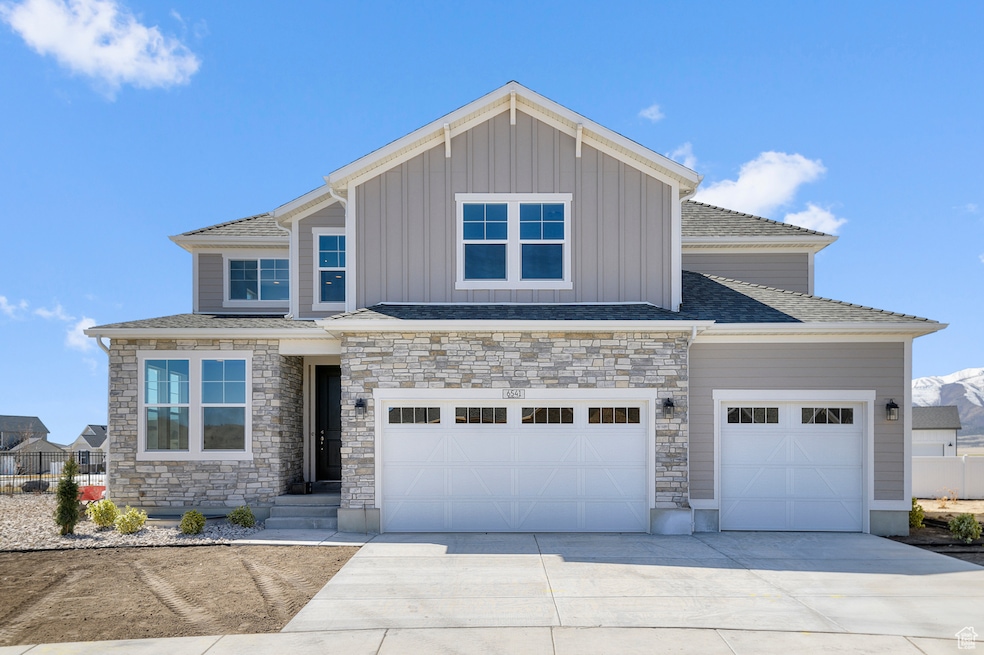 Craftsman-style house featuring concrete driveway, board and batten siding, stone siding, and an attached garage