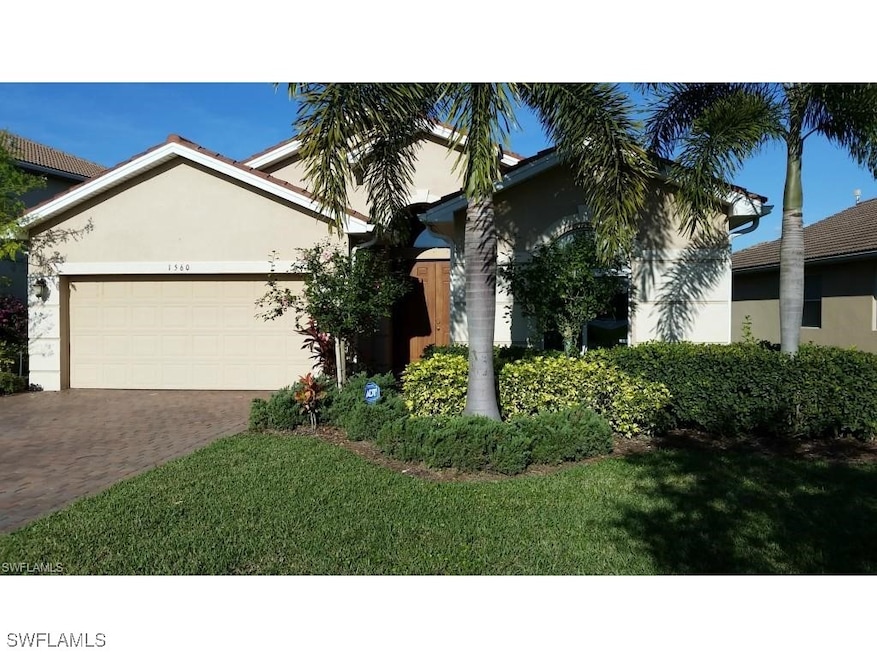 View of front facade featuring decorative driveway, a garage, stucco siding, and a front lawn
