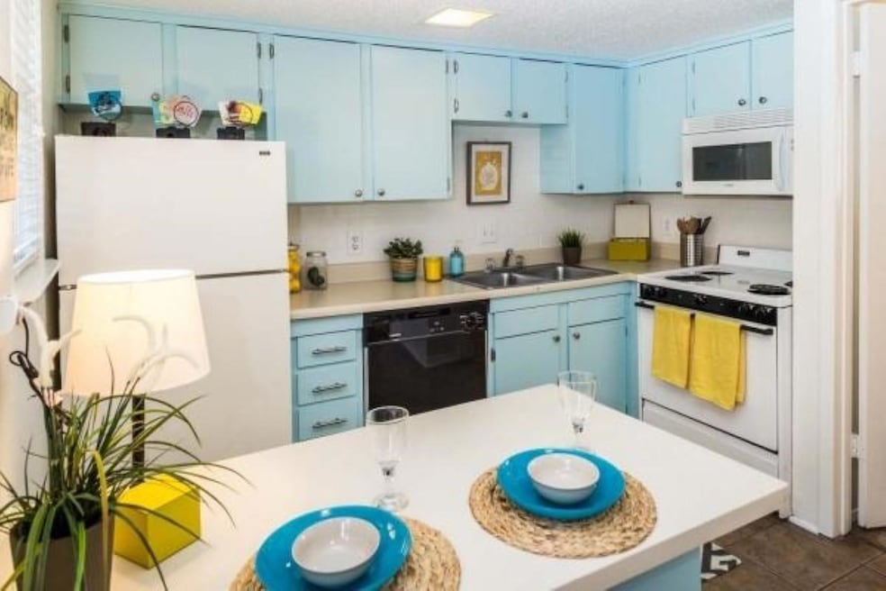 Kitchen with white appliances, blue cabinets, lig
