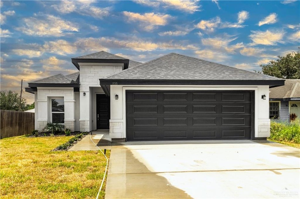 View of front of property featuring a garage and a front lawn