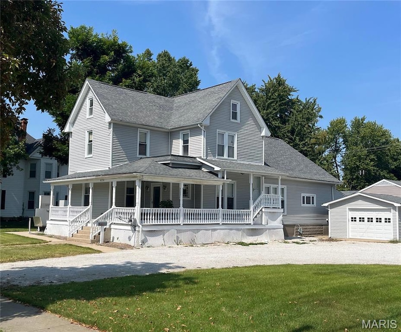 View of front of house with a porch, a front yard, an outdoor structure, and a shingled roof