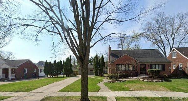 View of front of home featuring brick siding, a chimney, and a front lawn