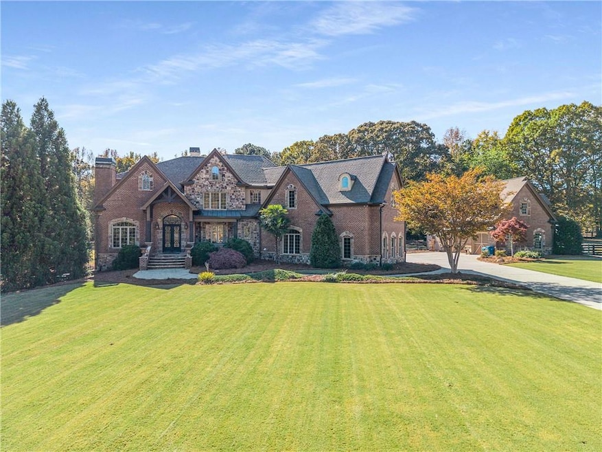 View of front of house featuring a chimney, a front yard, stone siding, and concrete driveway