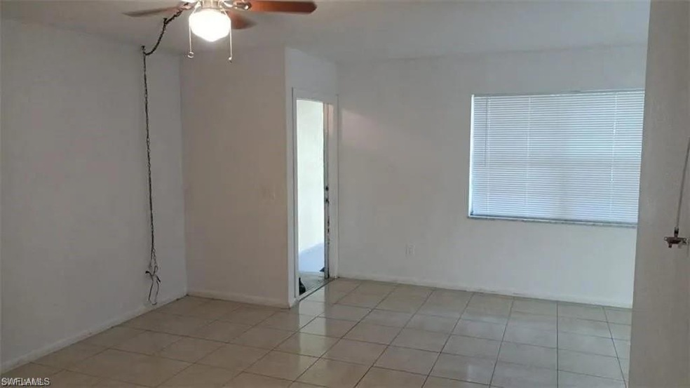 Empty room with a ceiling fan and light tile patterned flooring