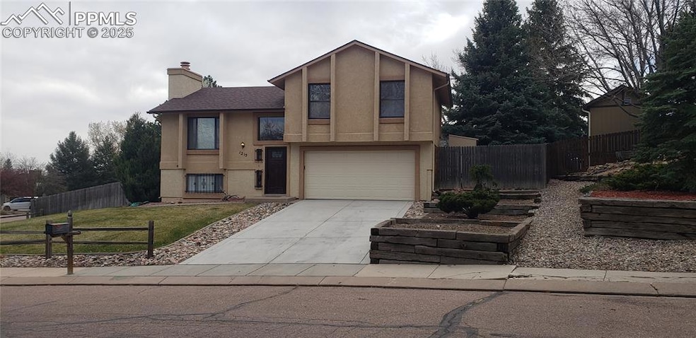 Raised ranch featuring a garage, a chimney, fence, stucco siding, and driveway