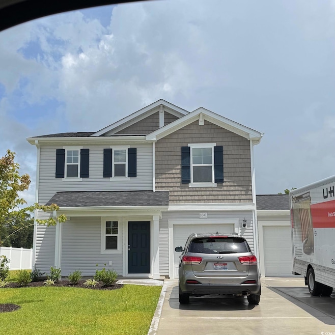 View of front of house with concrete driveway, an attached garage, and a shingled roof