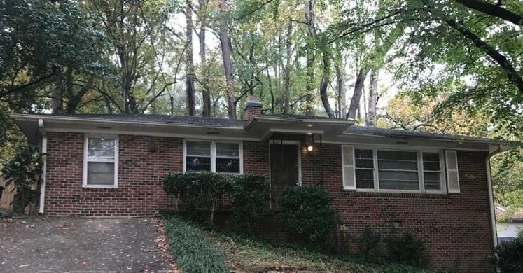 View of front facade with brick siding, a chimney,