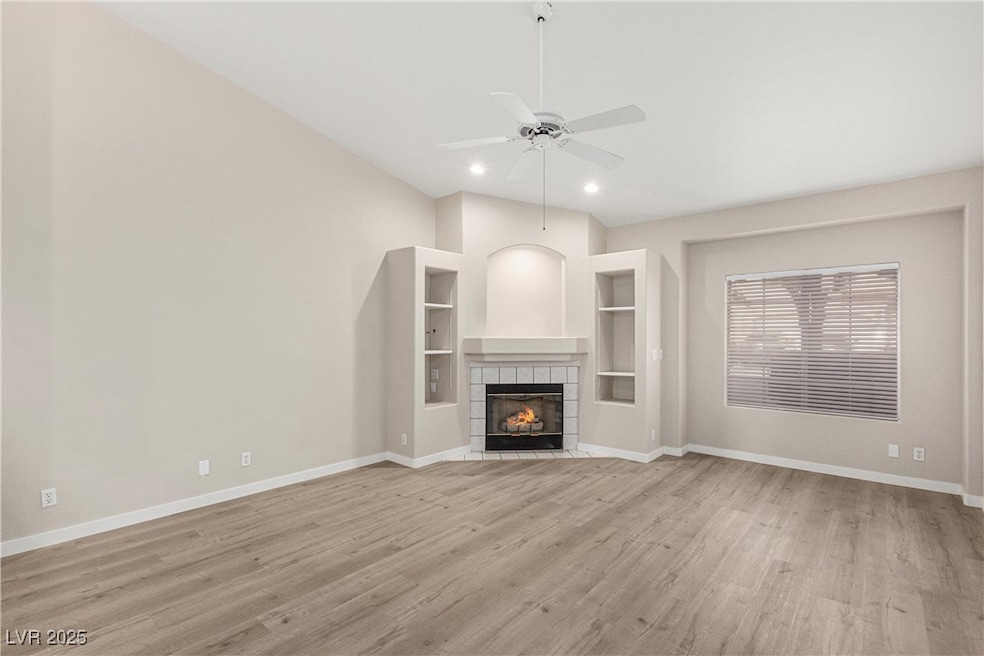 Unfurnished living room with a tiled fireplace, light wood-type flooring, a ceiling fan, recessed lighting, and built in features