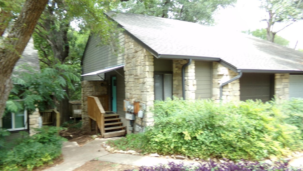 View of front of home featuring stone siding, roof with shingles, and a garage