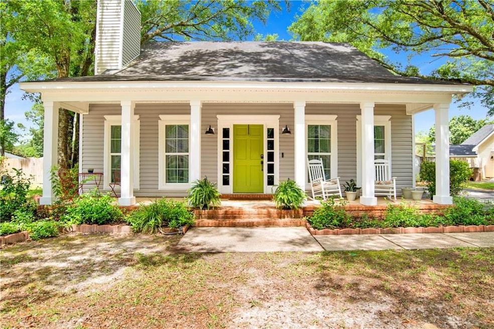 View of front of home featuring a chimney, a porch, and a shingled roof
